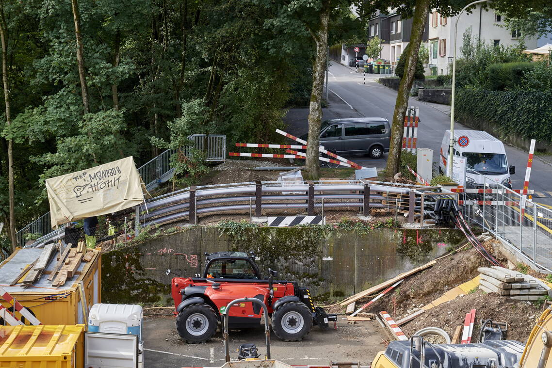 Weihnachtsschmuck verziert ein Baustellengitter, im Hintergrund ein Mehrfamilienhaus