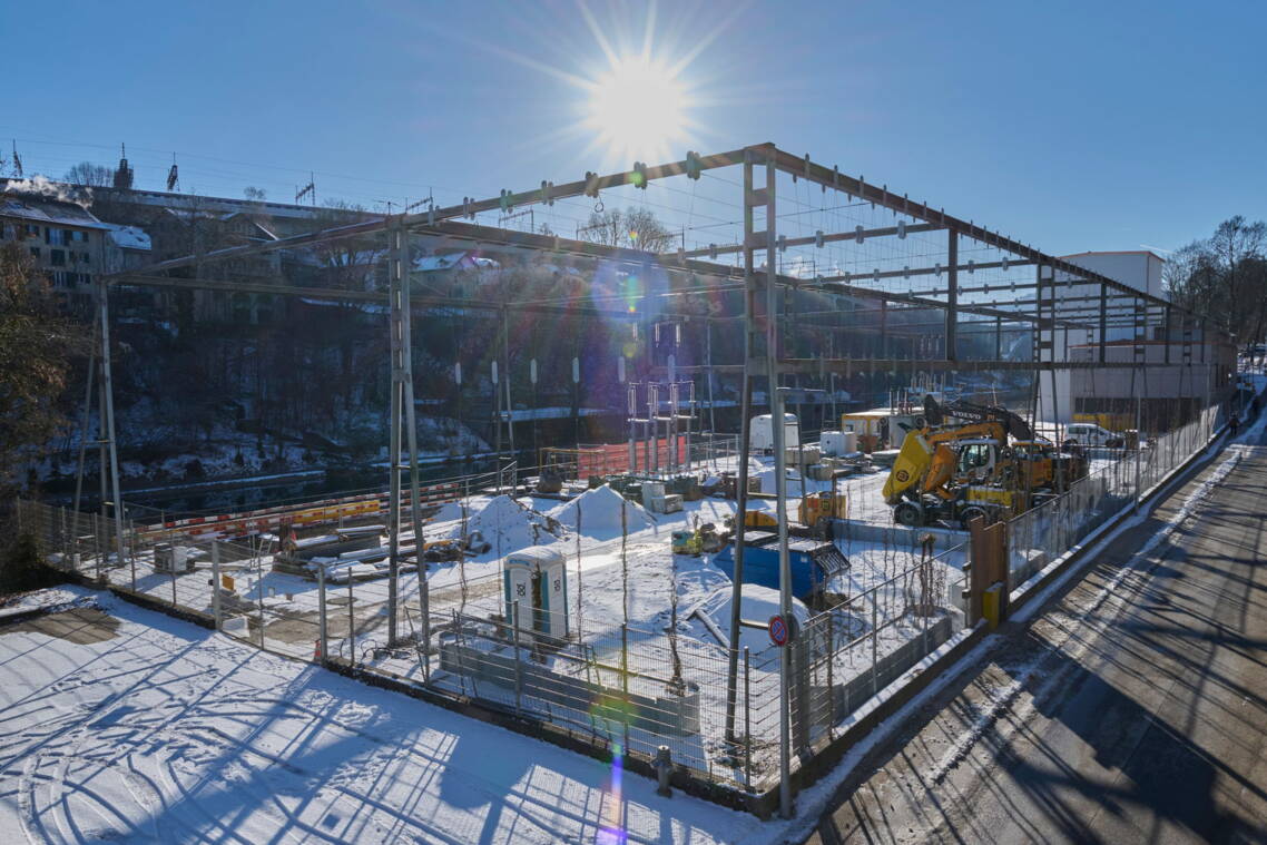 Weihnachtsschmuck verziert ein Baustellengitter, im Hintergrund ein Mehrfamilienhaus